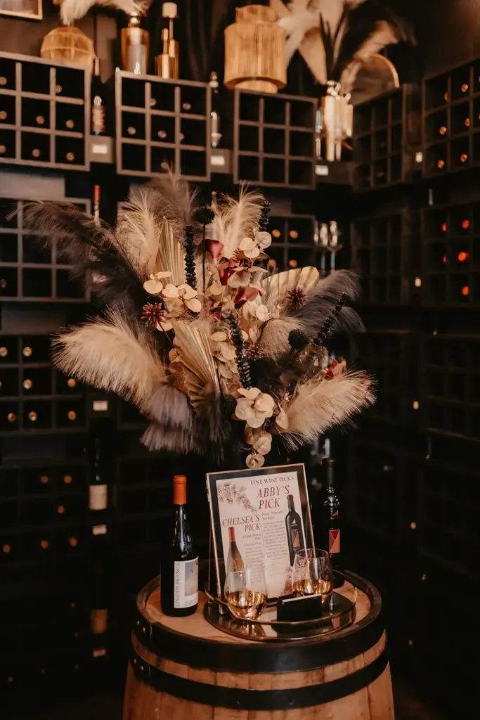 two wine bottles on either side of a picture frame and a feather bouquet 